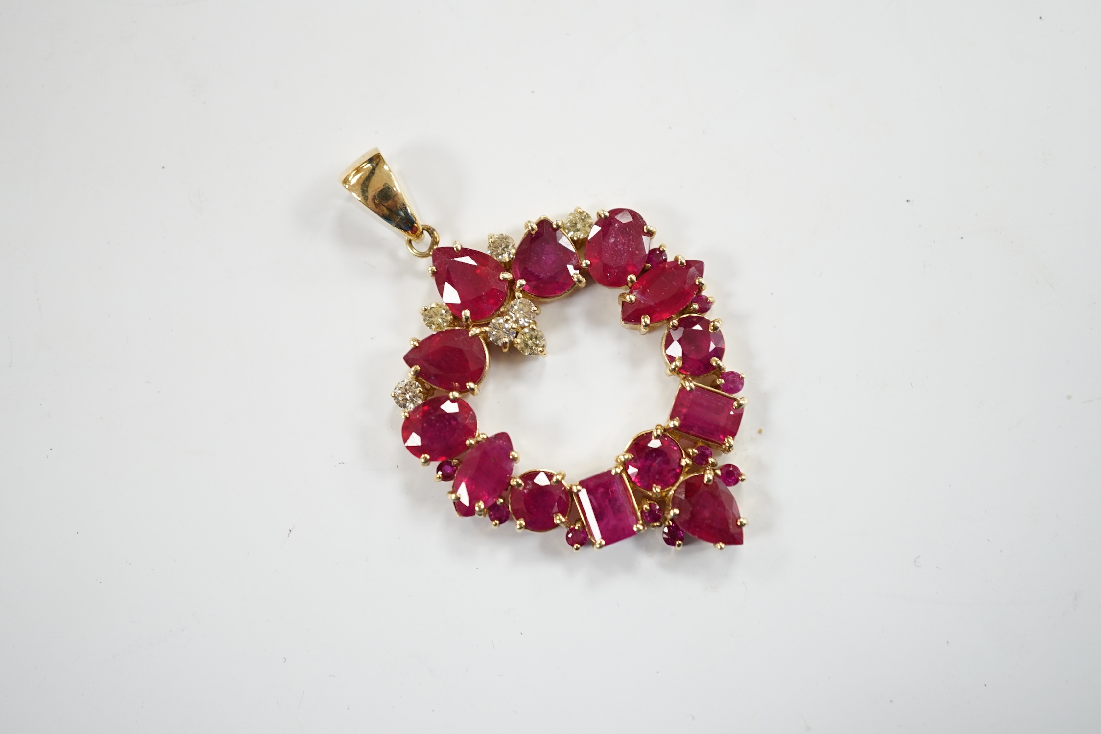 A modern 14k, ruby(treated) and diamond cluster set open work pendant, overall 52mm, gross weight 10.9 grams.